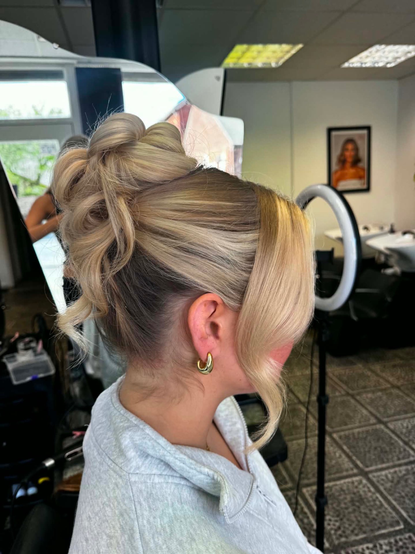 Blonde high updo with curled volume and soft tendrils